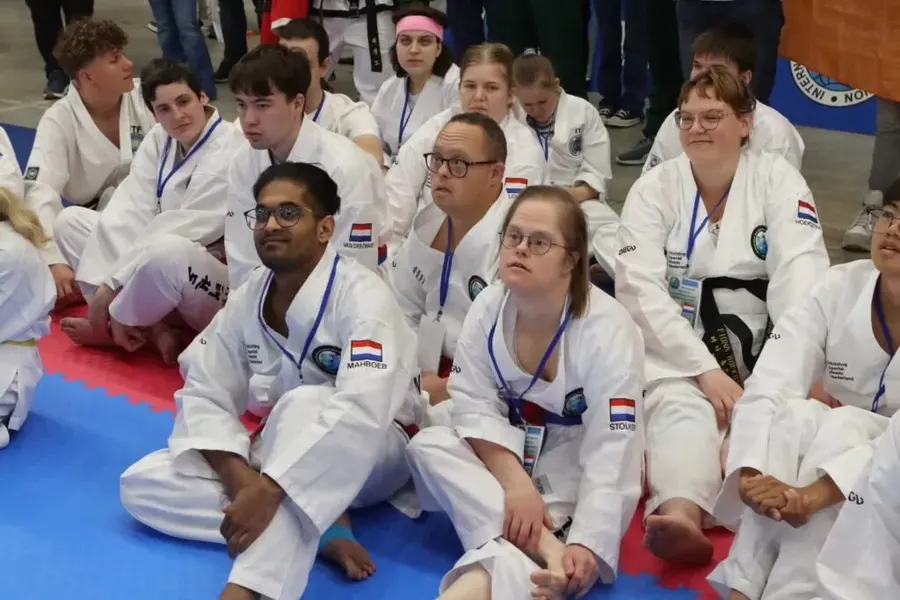Group of inclusive Taekwon-Do students seated together at an international event